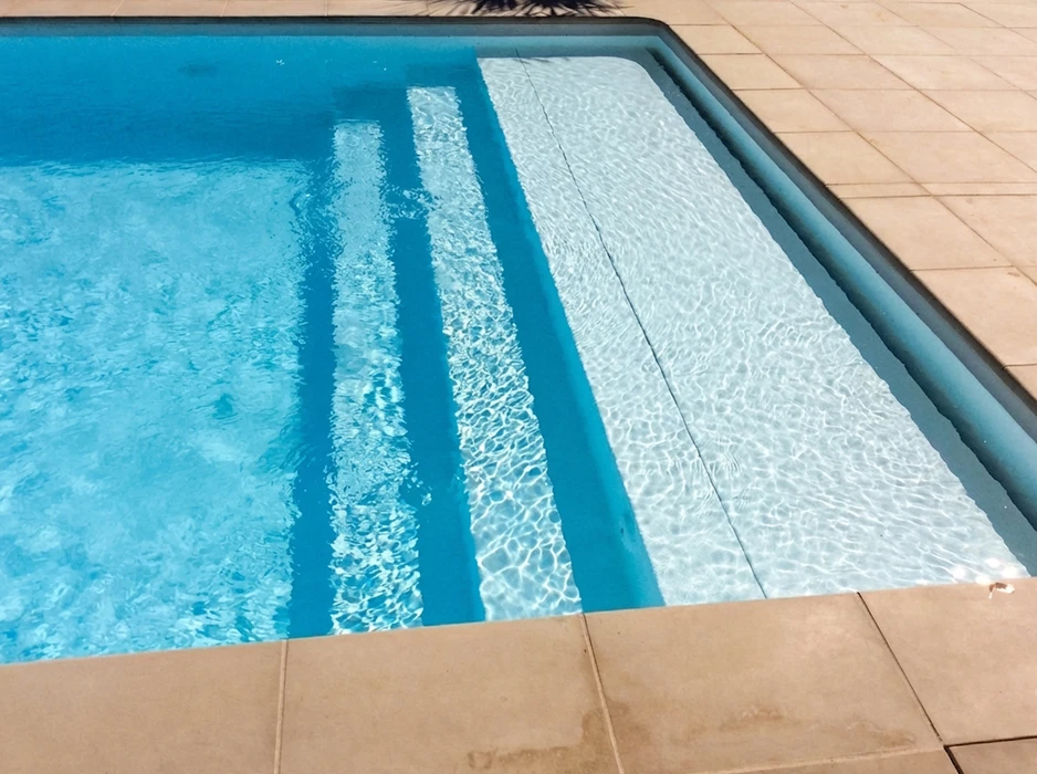 Piscine extérieure rectangulaire, eau cristalline bleu turquoise, éclairée en plein soleil