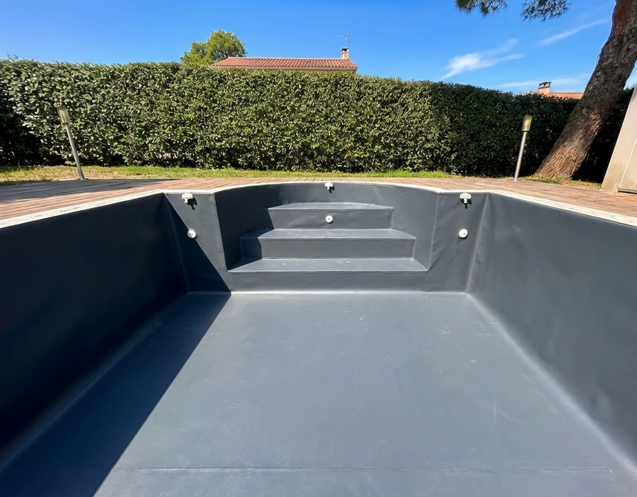 Piscine vide vue de l'intérieur, extérieur résidentiel, jardin avec haie taillée et terrasse en bois composite