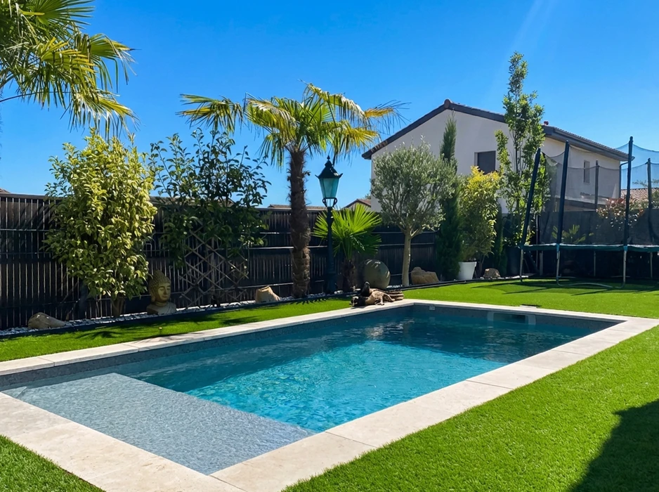 Piscine rectangulaire extérieure aux eaux turquoise cristallines, entourée d'un jardin méditerranéen avec palmiers et végétation luxuriante