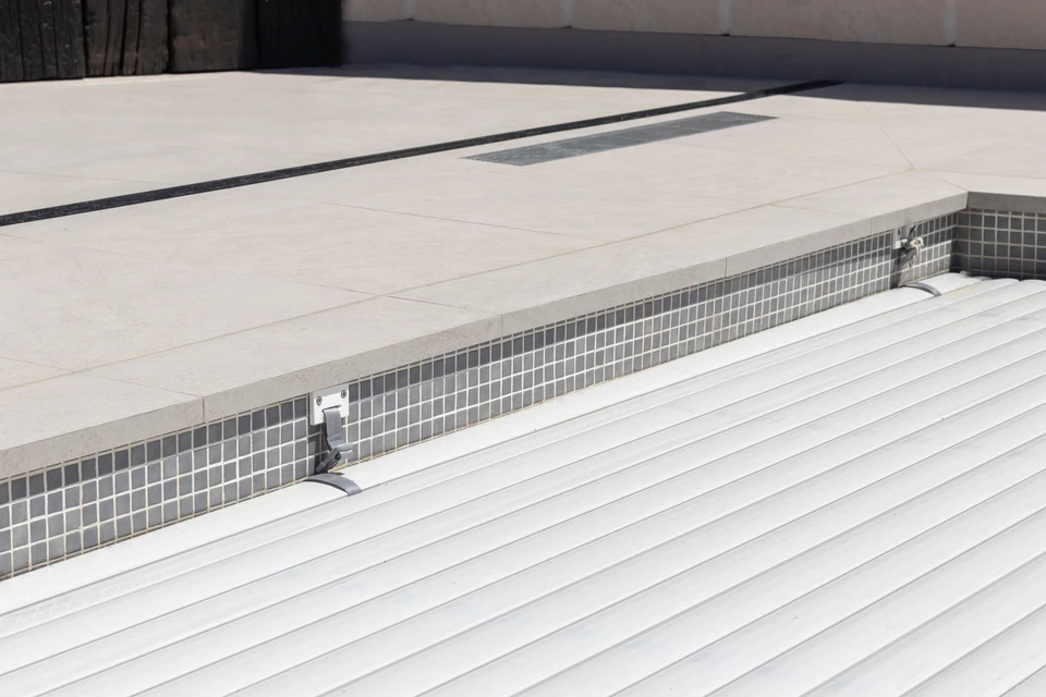 Piscine rectangulaire en cours de remplissage, liner PVC armé anthracite texturé, projecteurs LED encastrés en inox, escalier intégré à marches larges, niche de volet roulant immergé
